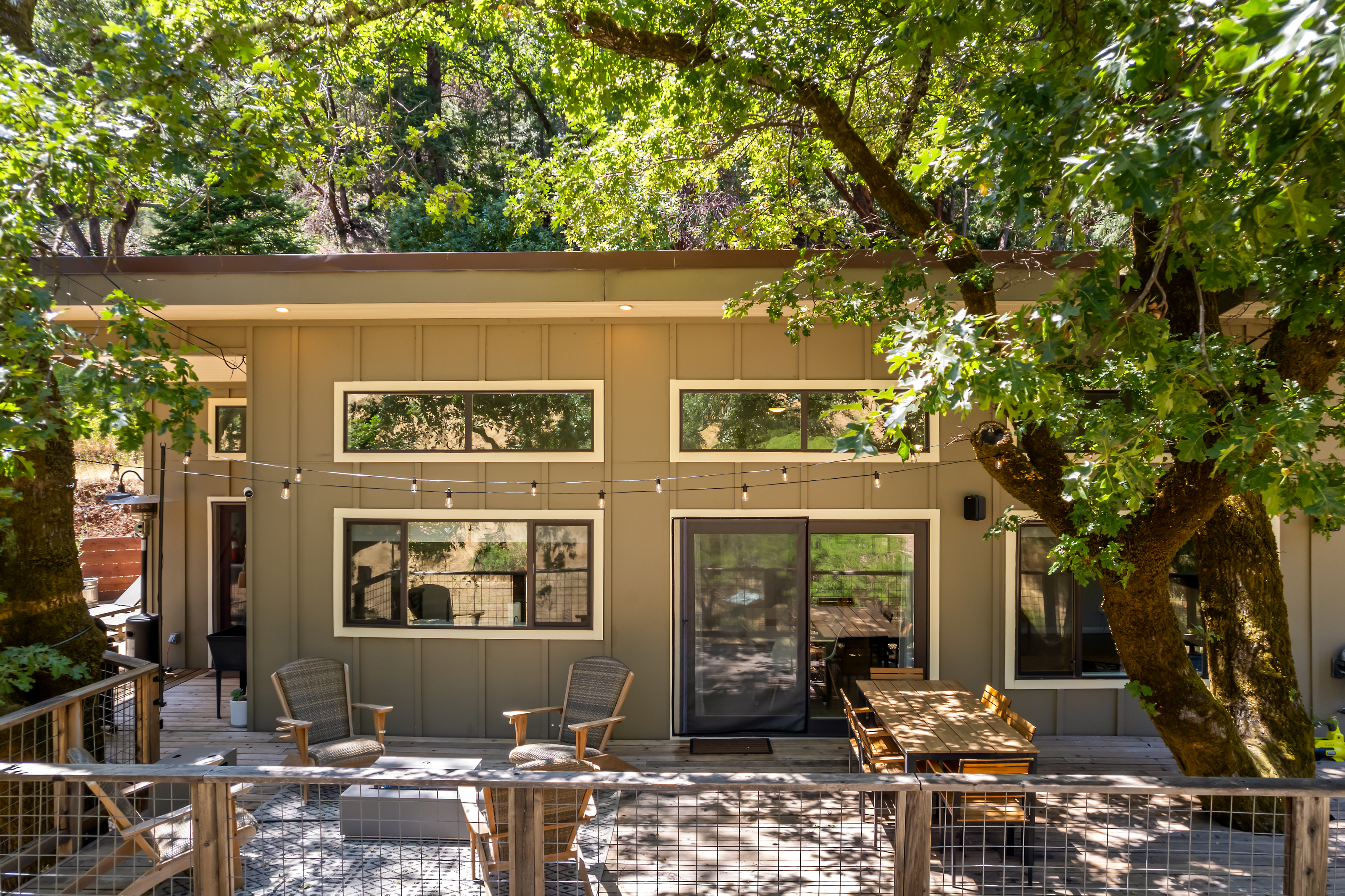 Modern farmhouse exterior nestled under oak trees