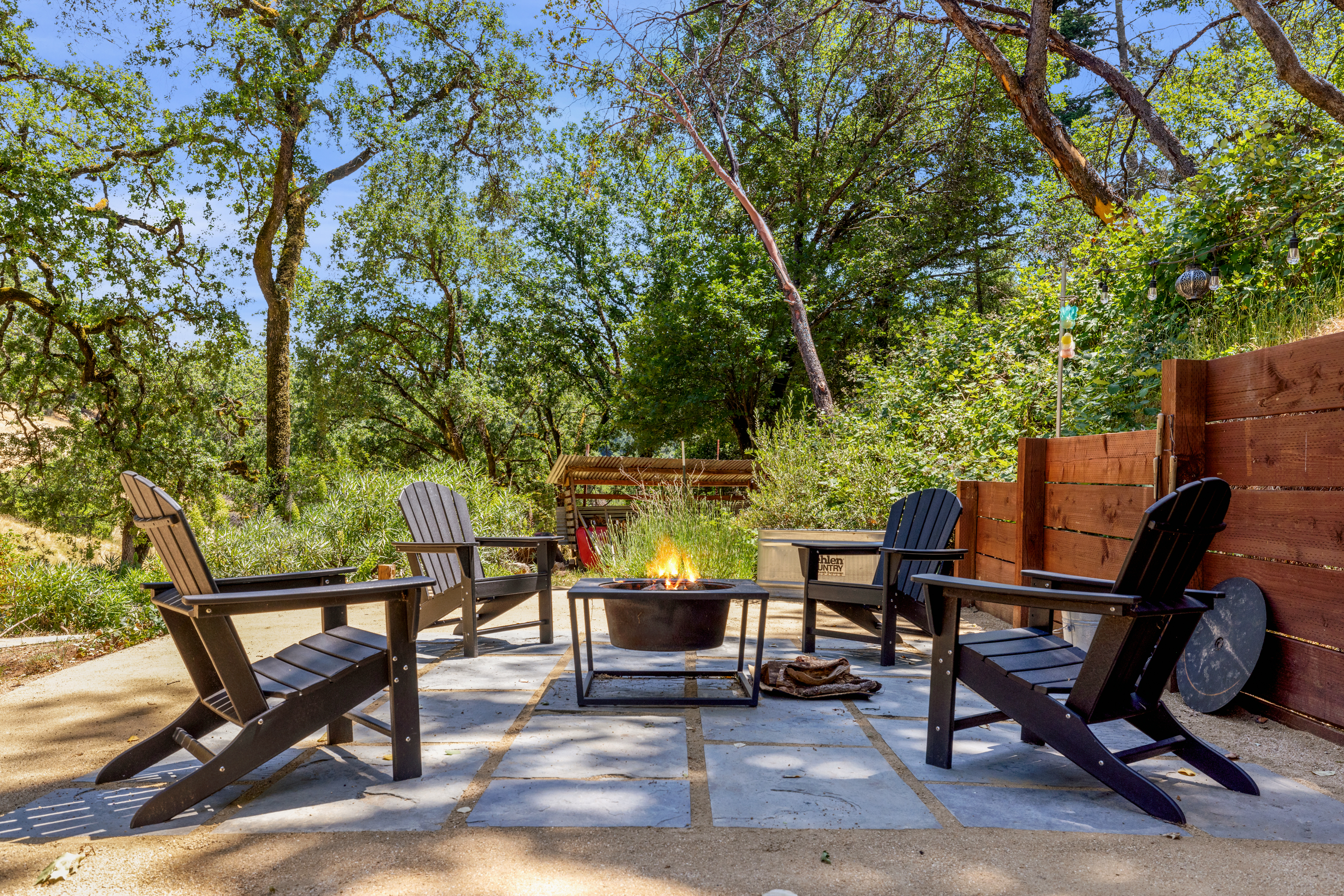 Fire pit with Adirondack chairs under oak trees